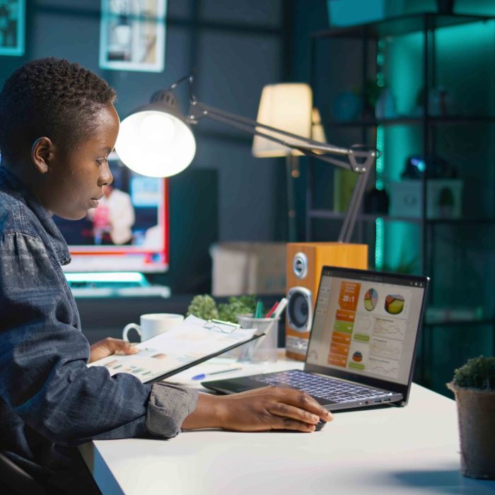 Entrepreneur working from home, using laptop, writing notes on paper. Remote worker in personal apartment office transcribing important info on notepad, looking at statistic charts, camera B